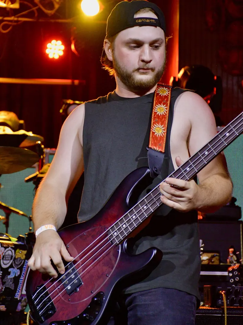 Bassist in a cap playing a red bass