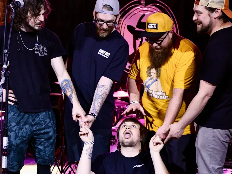 Band members dragging a bandmate across the floor
