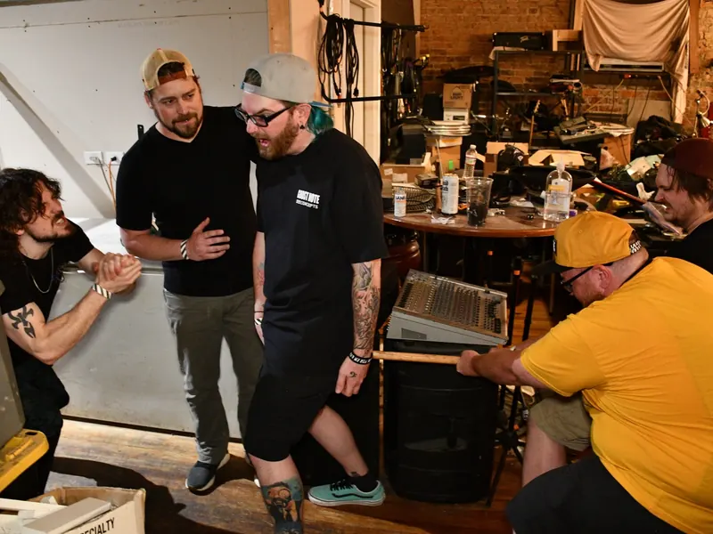Band members posing in a cluttered backstage room