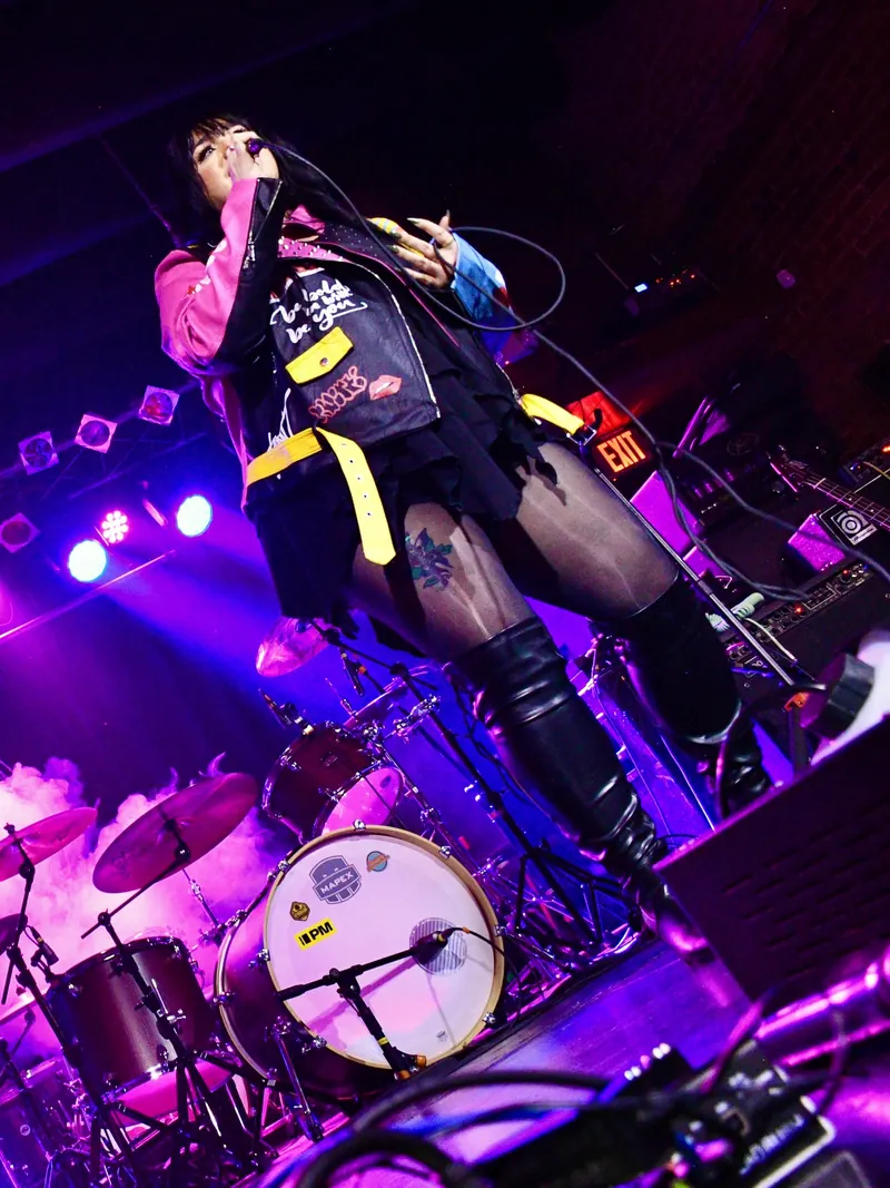 Low angle of Laken of Eye Candy under purple light, drum kit behind