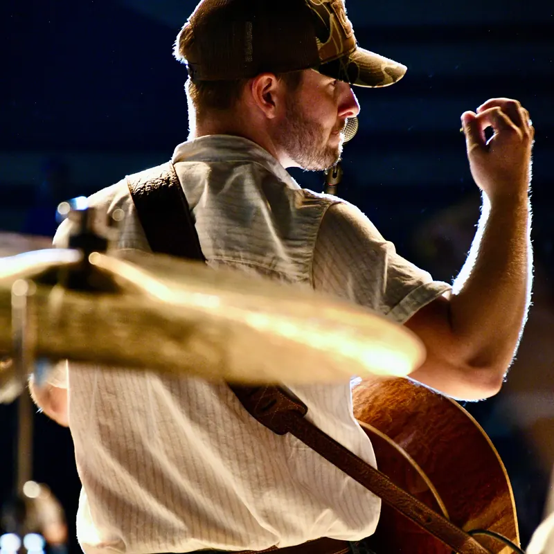 Guitarist backlit behind a cymbal
