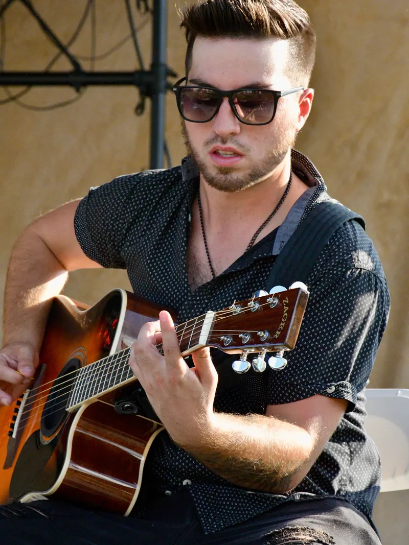 Guitarist in sunglasses playing an acoustic guitar
