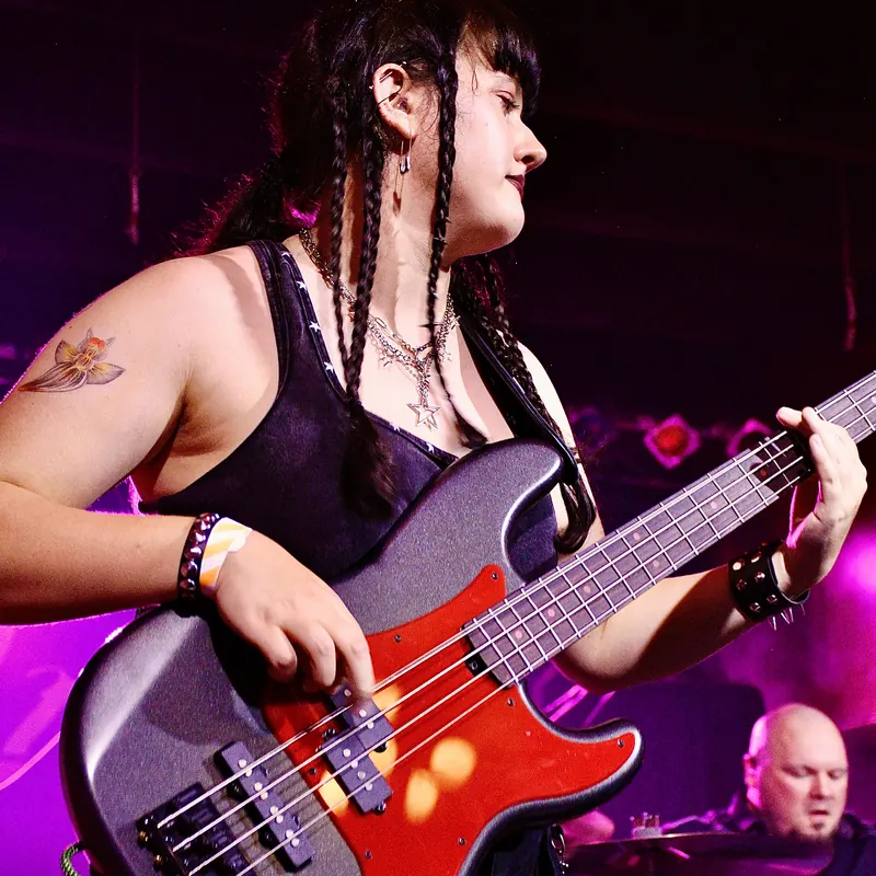 Bassist with braids playing under magenta light